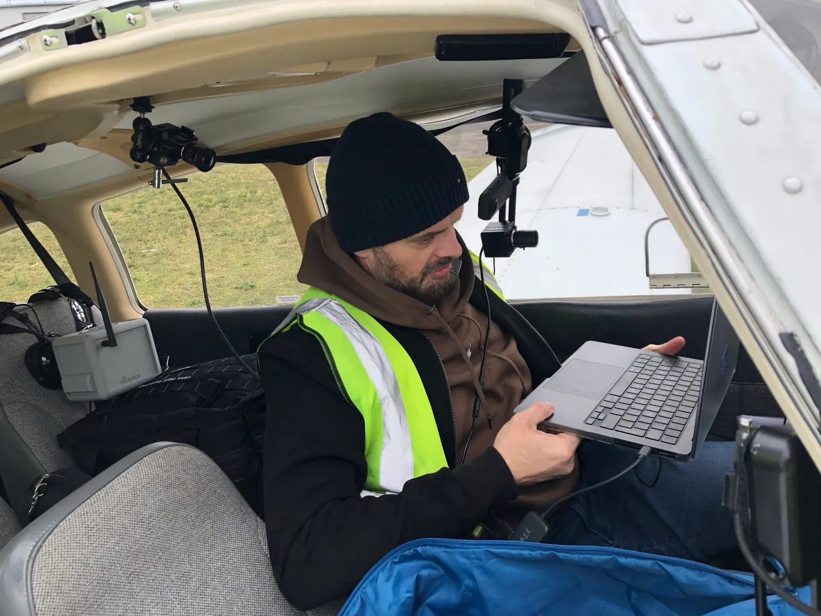 Greg in a hi-vis jacket working on a laptop in the cockpit